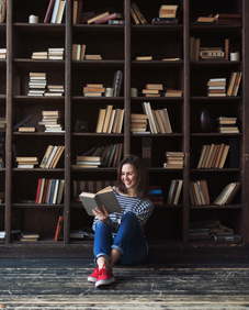Student Reaching For Book On Shelf